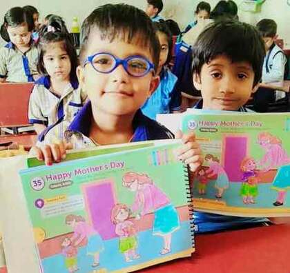 Young students holding Mother's Day craft cards they made in class