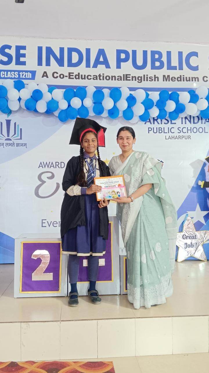 A graduating student in cap and gown receiving a certificate from the principal on the second-place podium